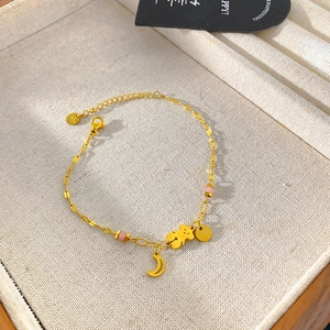 Detail of gold titanium steel bracelet with bear, moon charms and pink beads