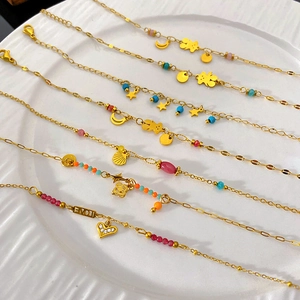 Detail of multiple gold-plated bracelets with colorful beads and various charm pendants