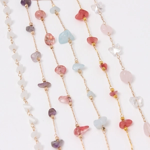 Detalle de cuentas de cristal multicolor en cadenas doradas finas con dije de mariposa