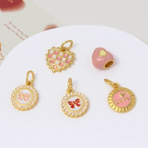Pink heart and bow enamel charms for DIY jewelry making on a white display plate