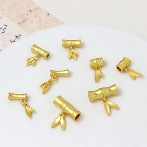 Ancient gold bamboo style beads and leaf pendants set on elegant white display tray