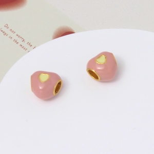 Macro detail of heart-shaped pink enamel beads with yellow heart for DIY jewelry making