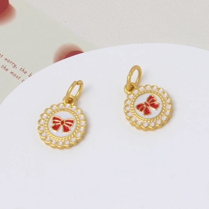 Close-up of golden enamel heart charms with red bows for DIY jewelry accessories