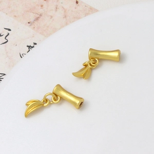 Macro detail of matte gold bamboo joint charms with hanging leaves for jewelry DIY