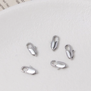 Macro di cinque chiusure a moschettone in argento placcato oro 18K su piatto bianco