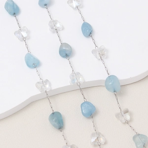 Detalle de piedras azules irregulares y mariposas de cristal en una cadena de plata