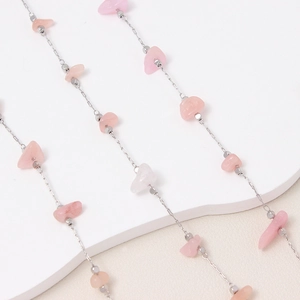 Detalle de cuentas de cristal de piedra rosa en cadena de cobre plateado para joyería