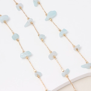 Detalle de piedras de cristal azul claro en cadena dorada para creación de joyería DIY
