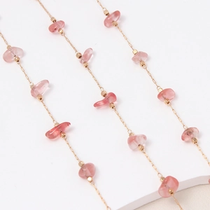 Detalle de cadena dorada hecha a mano con piedras de cristal natural rosa irregulares