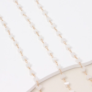 Vista macro de cadena dorada con cuentas de corazón blanco para joyería hecha a mano DIY