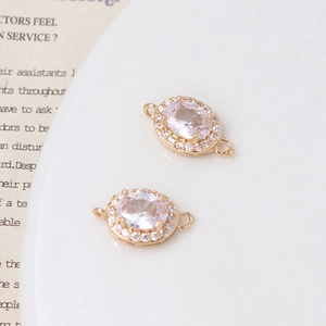 Nahaufnahme von ovalen Anhängern mit rosa Zirkonia in goldener Mikropavé-Fassung