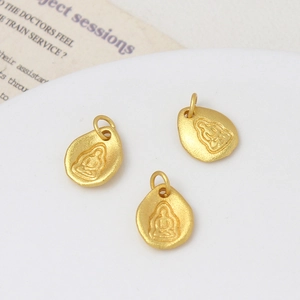 Macro-detail van drie zandgouden Boeddha-hangers met matte textuur voor DIY-sieraden