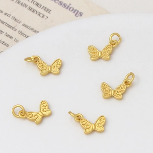 Detailopname van 5 matgouden vlinderhangers met elegante gegraveerde reliëfpatronen