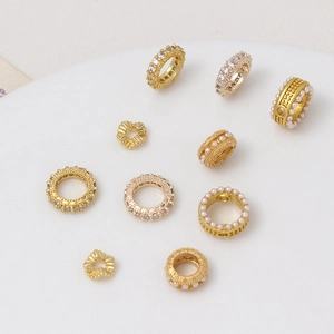 Surtido de cuentas espaciadoras doradas y dijes de perlas para joyería DIY en bandeja blanca