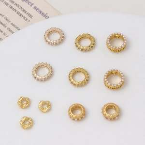 Selección de espaciadores dorados para joyas DIY con zircones y perlas en bandeja cerámica