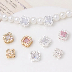 Detailed close-up of clover-shaped zircon spacers in gold and silver for jewelry making