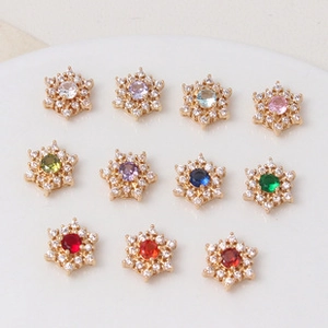 Macro detail of snowflake-shaped gold-plated spacers with multi-color zircon inlay