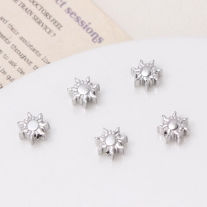 Dettaglio macro di 5 perline a forma di sole in argento lucido per orecchini fai-da-te