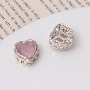 Vue macro de perles en cœur avec gemmes roses et dos ajouré pour création de bijoux DIY