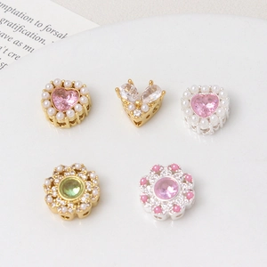Detailed macro of gold plated heart and flower charms with pearls for DIY jewelry