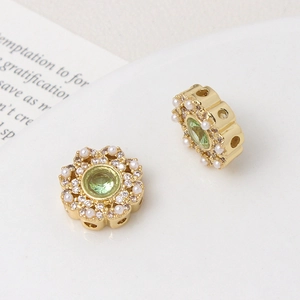 Macro detail of gold-plated flower charm with green stone, pearls and zircon inlay