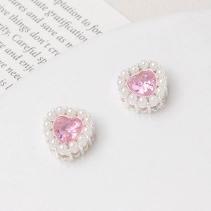 Detailed view of pink heart-shaped crystal charms with white pearls in silver setting