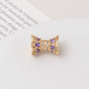 Macro shot of gold-plated hourglass bead with purple zircon and wavy pattern detail