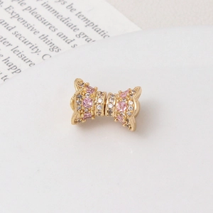 Macro view of a luxury gold bow charm with sparkling pink and white pavé zircon stones