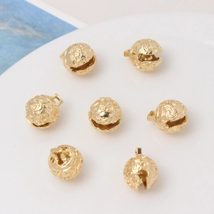 Detailed view of hollow gold-plated metal bell beads with intricate floral engraving patterns
