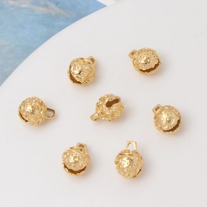 Close-up of seven gold-plated hollow spherical bells with star patterns for DIY jewelry