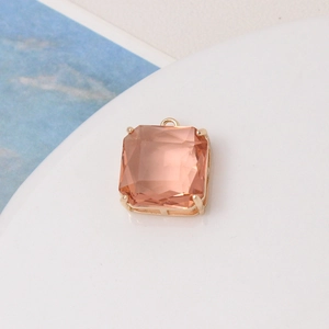 Macro shot of champagne pink square faceted glass charm with 4-prong metal setting