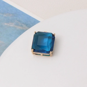Macro shot of dark blue faceted crystal charm with a four-prong gold metal setting