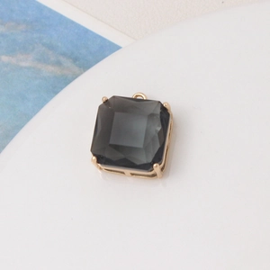 Macro detail of dark grey faceted square stone pendant with gold four-prong setting