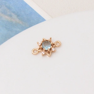 Macro shot of gold-plated sun pendant with light blue zircon and symmetrical double loops