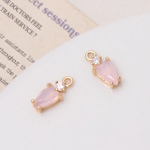 Close-up of elegant pink teardrop zircon charms with gold metal frames for DIY jewelry