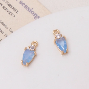 Close-up of light blue teardrop crystal pendant with gold setting and small zircon accent
