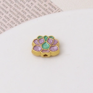 Macro detail of gold lotus bead with purple and green enamel inlay for DIY jewelry making