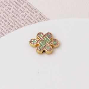 Macro detail of ancient gold knot charm with pink and green glitter enamel inlay