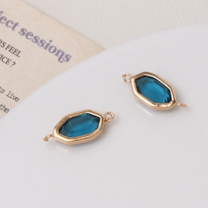 Detail van twee goudomrande zeshoekige blauwe kristalconnectoren voor DIY-sieraden