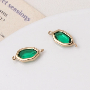 Macro-opname van smaragdgroene glazen hangers met gouden frames voor DIY-sieraden