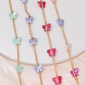 Macro detail of gold-plated butterfly chains with colorful acrylic charms and soft luster