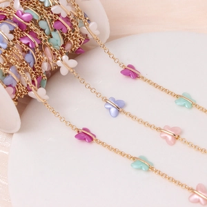 Gold plated link chain with colorful acrylic butterflies on a white spool for DIY jewelry