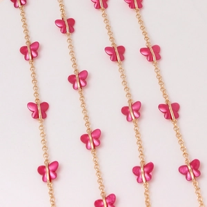 Detailed macro view of gold-plated O-chains featuring metallic magenta butterfly links