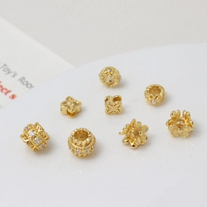 Close-up of gold-plated flower beads and clover spacers with zircon for DIY jewelry