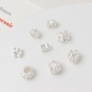 Macro detail of silver plated flower spacer beads and zircon charms for jewelry making