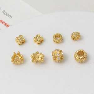 Detailed view of eight gold plated spacer beads with zircon and floral DIY jewelry designs