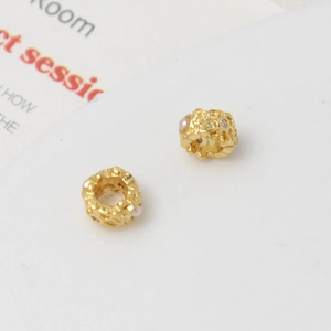 Detailed macro view of gold-plated spacer beads with zircon and pearl inlay for DIY jewelry