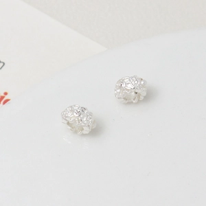 Macro shot of silver spacer beads with floral engravings and inlaid white stones