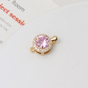 Detailed macro view of a gold-plated circular clasp with a faceted pink zircon stone
