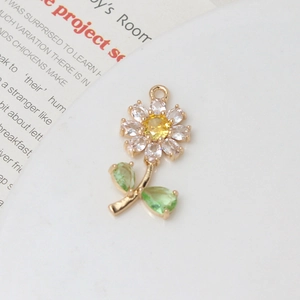 Macro shot of gold daisy flower pendant with sparkling cubic zirconia and green leaves
